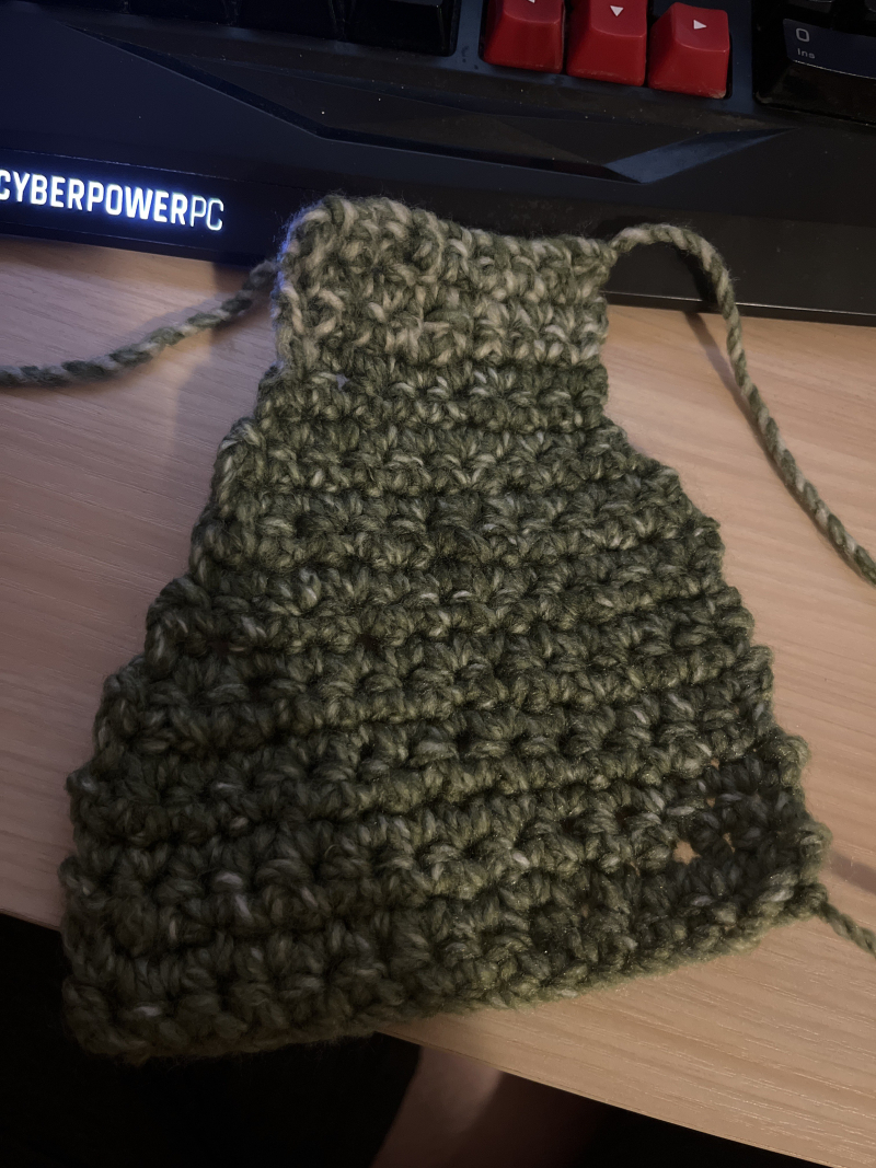 a lopsided swatch of crocheted green yarn that tapers towards the top.